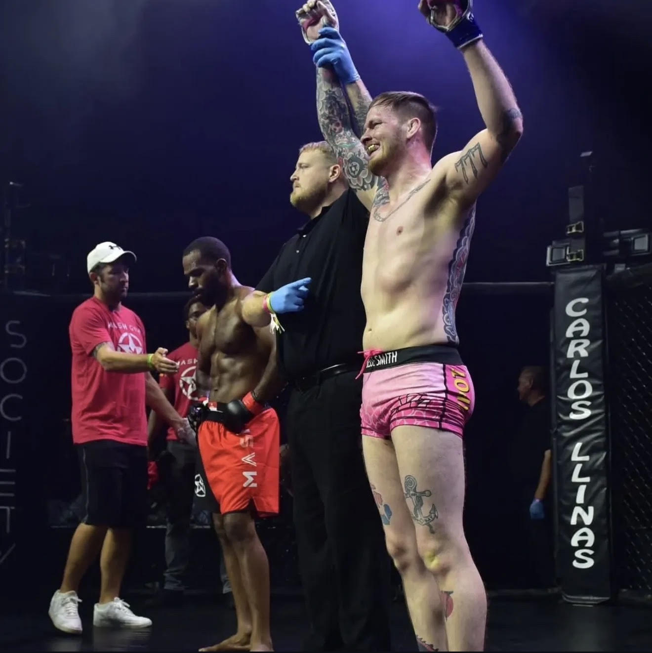 Fighter celebrating victory with arms raised in the octagon